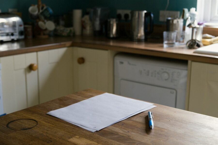 Person writing small habit list kitchen table