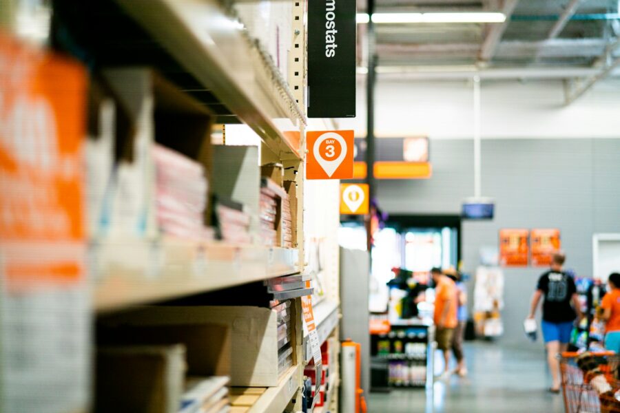 Person comparing prices phone supermarket shelf