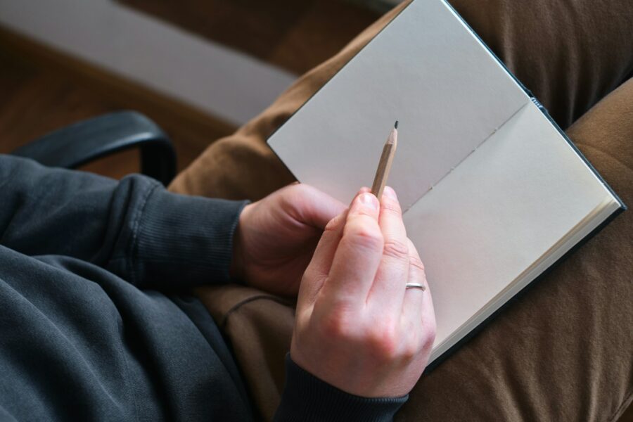 Person journaling couch notebook pen