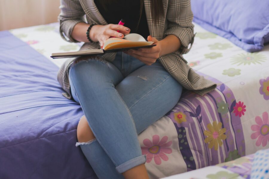 Woman sitting bed soft light evening notebook blanket