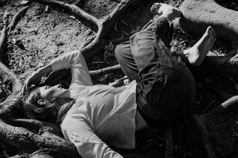 Monochromatic portrait of person lying among tree roots, reflecting serenity.