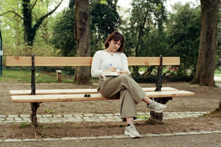 Park bench trees walking path notebook pen coffee